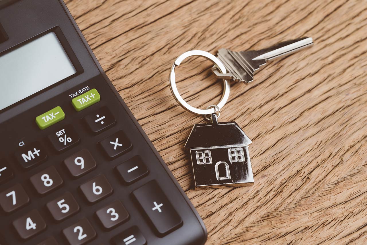 Home key with house keyring with black calculator on wooden table