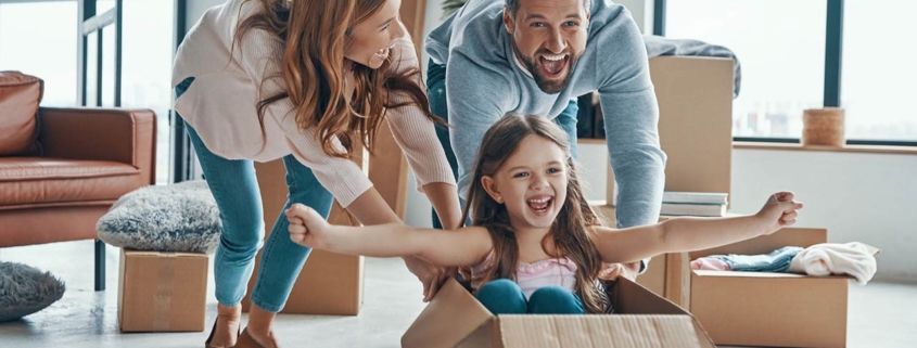 Cheerful young family smiling and unboxing their stuff while moving into a new apartment