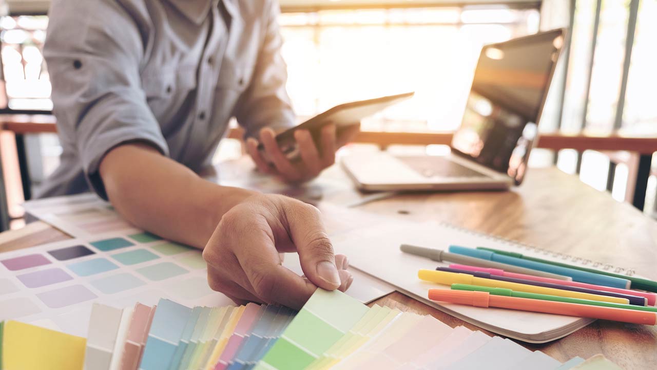 Man with laptop and paint swatches to select a new color