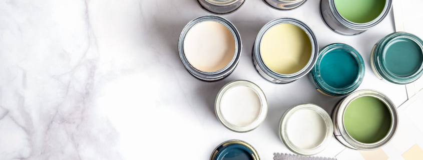 Tiny sample paint cans during house renovation, process of choosing paint for the walls, different green and beige colors, color charts on marble background