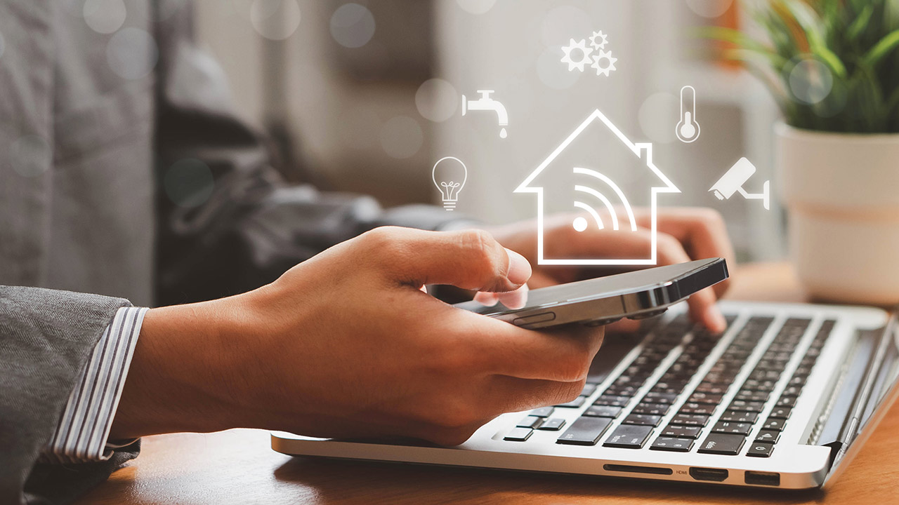 Person using a smart home app on a phone and laptop