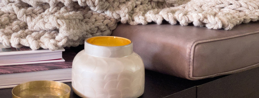 Warm comfy living room setting with candle and chunky afgan with thick gray yarn stock photo